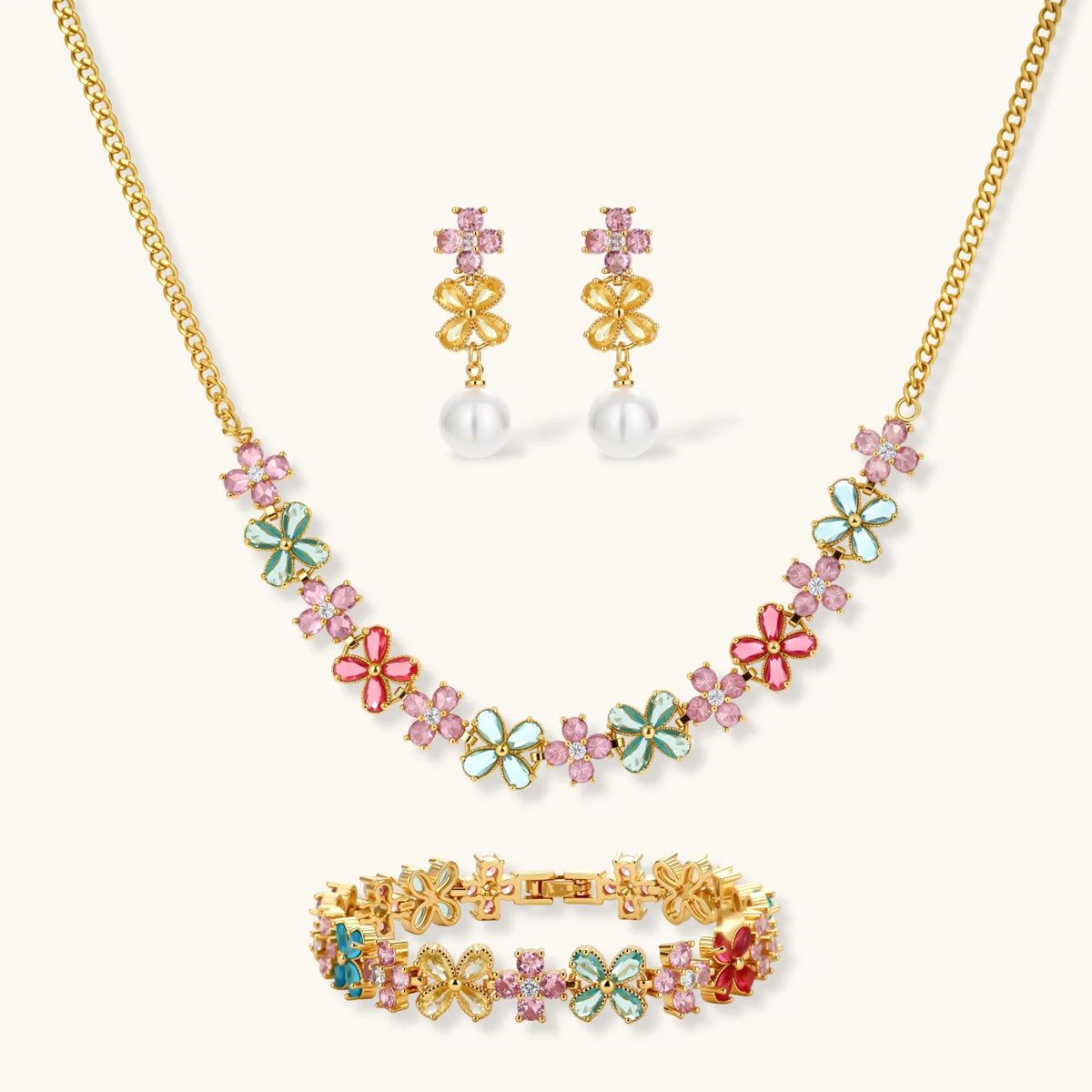 Gold-plated jewelry set with pink, turquoise and red flower-shaped cubic zirconia stones, featuring necklace, earrings and bracelet.