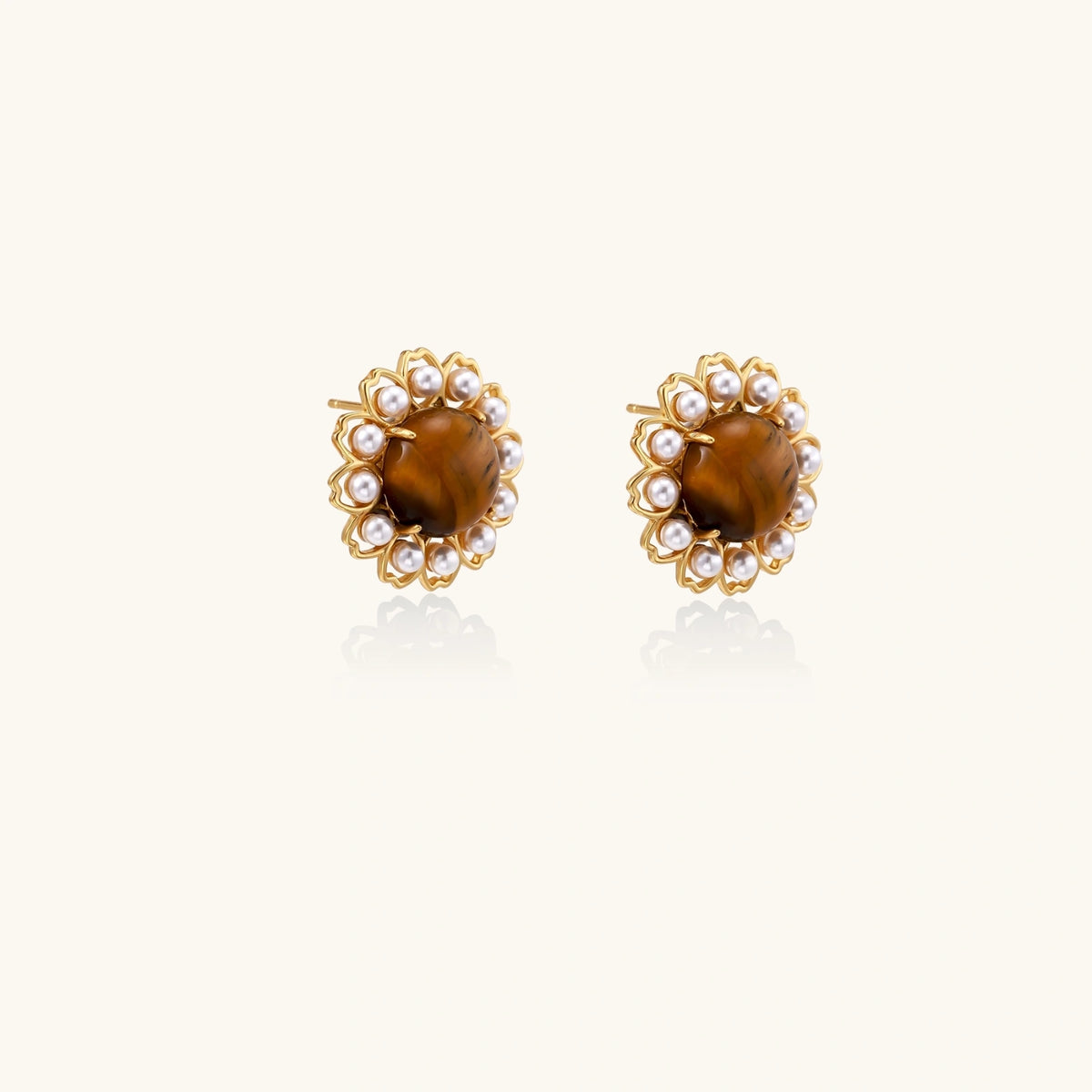Gold-plated stud earrings with cushion-cut tiger's eye stones surrounded by pearl halos on white background.