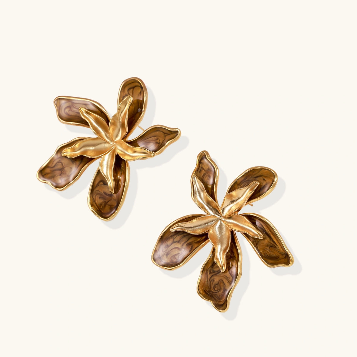 Gold-plated brass flower earrings with brown tortoiseshell enamel petals on cream background