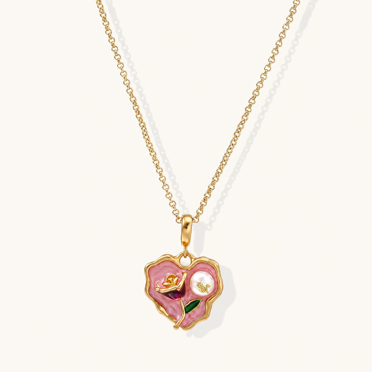 Heart-shaped pendant with pink enamel, rose design, freshwater pearl flower, and gold scalloped frame on delicate chain
